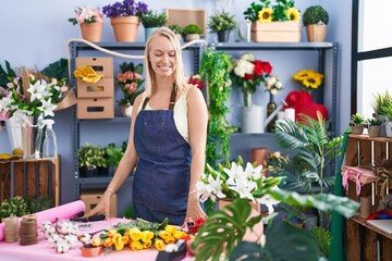Young blonde woman florist make bouquet of flowers at florist store