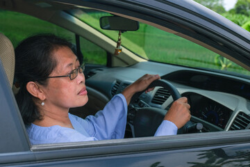 Obraz premium female driver looking at car side mirror from her seat behind the steering wheel to make a right turn
