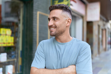 Young hispanic man standing with arms crossed gesture at street