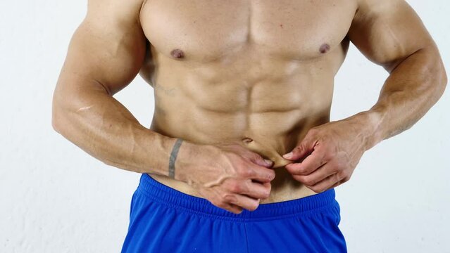 Fit, athletic muscular man pinching his stomach skin