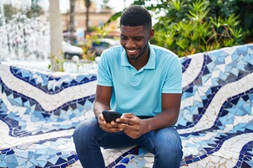 Obraz premium Young african american man smiling confident using smartphone at park