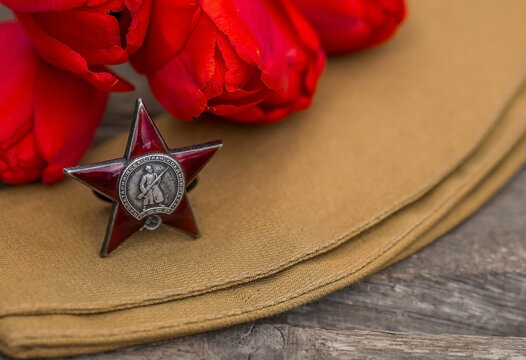 St. George's ribbon and the Order of the Red Star of the USSR World War II veteran on a wooden background. Translation into Russian: Workers of all countries unite. The concept of the May 9 holiday.