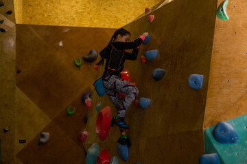 little girl climbing a rock wall indoor
