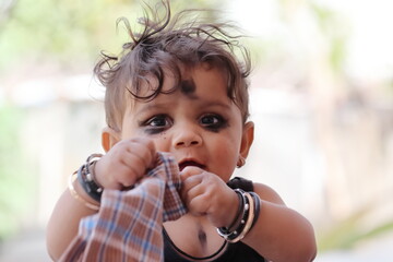 Close-up photo of Beautiful little indian hindu baby smiling looking at the camera and holding blur Handkerchief in hand