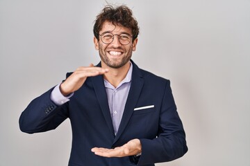 Hispanic business man wearing glasses gesturing with hands showing big and large size sign, measure symbol. smiling looking at the camera. measuring concept.