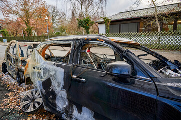 Wrecks of two burnt out cars on the side of the road.