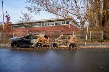 Wrecks of two burnt out cars on the side of the road.