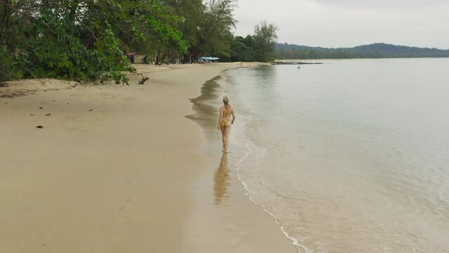 Aerial view of a girl in a swimming suit walking on a sand beach in Phu Quoc Island, Vietnam