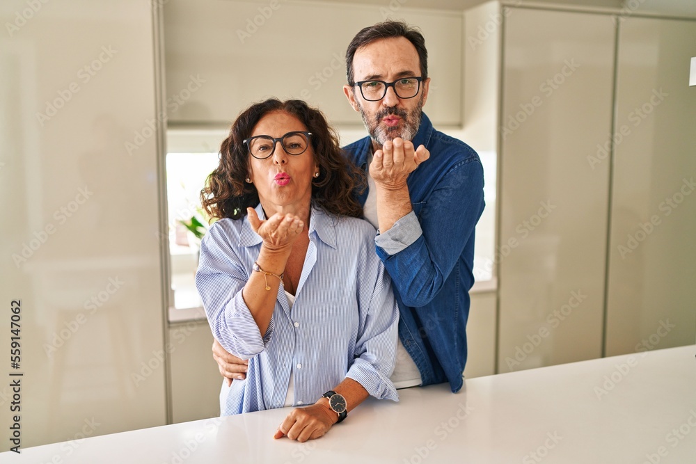 Sticker Middle age couple standing together looking at the camera blowing a kiss with hand on air being lovely and sexy. love expression.