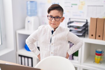 Obraz na płótnie Canvas Adorable hispanic boy business worker standing with serious expression at office