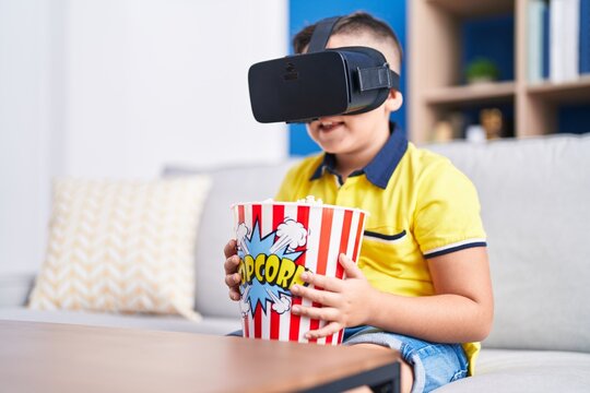 Adorable hispanic boy watching 3d movie sititng on sofa at home