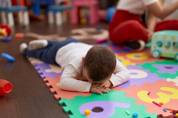 Adorable toddler lying on floor crying at kindergarten - obrazy, fototapety, plakaty