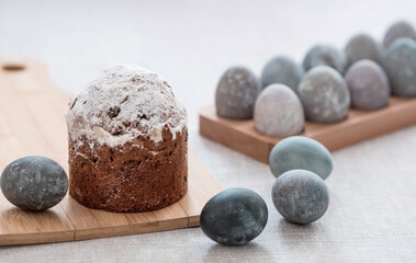 Stylish grey Easter eggs in marble and concrete and a cake on a wooden stand. Coloring eggs with natural dye karkade tea. Environmental friendliness. Naturalness. The concept of happy Easter 2023.