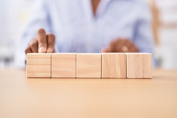 Middle age african american woman business worker sitting on table with wooden cubes at office