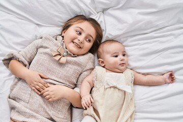 Brother and sister smiling confident lying together on bed at bedroom