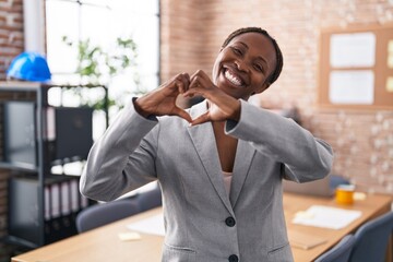 African american woman at the office smiling in love showing heart symbol and shape with hands....