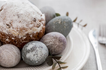 Spring table setting. A plate with a cotton napkin with a bunny, a cake and Easter eggs. Silverware, Easter bunnies and a vase of flowers on a linen tablecloth. The concept of a bright Easter holiday.