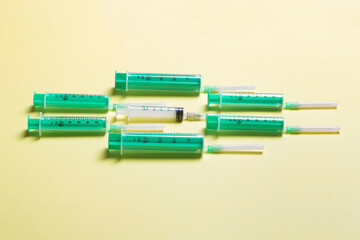 Obraz premium Top view of medical syringes with needles at yellow background with copy space. Injection treatment concept
