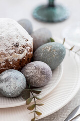 Spring table setting. A plate with a cotton napkin with a bunny, a cake and Easter eggs. Silverware, Easter bunnies and a vase of flowers on a linen tablecloth. The concept of a bright Easter holiday.