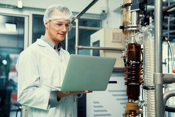 Apothecary scientist working with laptop near CBD oil extractor and a scientific machine used to...