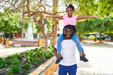 Father and daughter smiling confident holding girl on shoulders at park