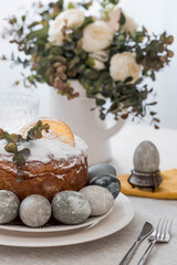 Spring table setting. A plate with a cotton napkin with a bunny, a cake and Easter eggs. Silverware, Easter bunnies and a vase of flowers on a linen tablecloth. The concept of a bright Easter holiday.