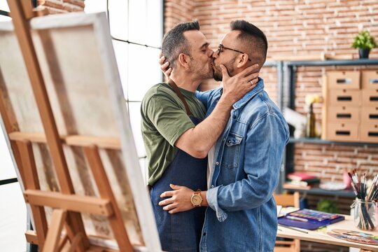 Two men artists hugging each other kissing at art studio