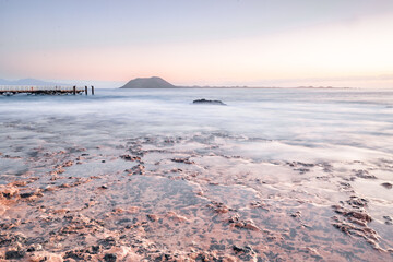 Long exposure over a lava beach. Stony sandy beach in the morning. bay, coast at Corralejo, Las Palmas Province, Spain