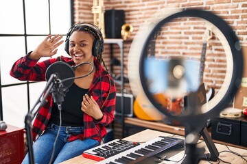 African american woman with braids recording music tutorial with smartphone at home looking positive and happy standing and smiling with a confident smile showing teeth