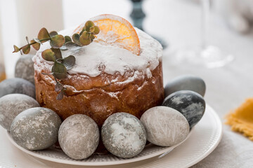 Spring table setting. A plate with a cotton napkin with a bunny, a cake and Easter eggs. Silverware, Easter bunnies and a vase of flowers on a linen tablecloth. The concept of a bright Easter holiday.