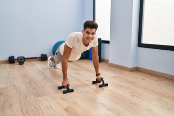 Young hispanic man smiling confident training push up at sport center