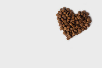 Dry pet food in the shape of a heart isolated on a white background. Granulated dietary food for...