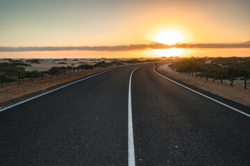 Fototapeta na wymiar Beautiful morning on a road through the dunes. Sunrise over a road with clouds. Corralejo National Park, Canary Islands, Spain