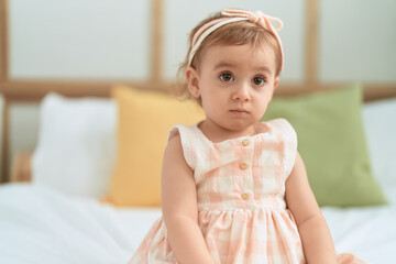Fototapeta premium Adorable caucasian girl sitting on bed with relaxed expression at bedroom
