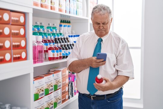 Middle age grey-haired man customer make photo by smartphone to medicine bottle at pharmacy