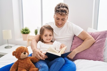 Father and daughter father and daughter reading book holding teddy bear at bedroom