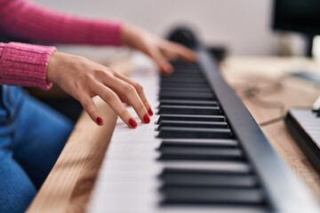 Obraz premium Young caucasian woman musician playing piano at music studio