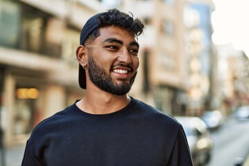Young arab man smiling confident wearing cap at street
