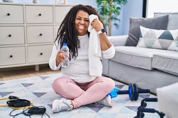 African american woman smiling confident holding water using towel at home