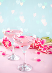 Glasses of pink cocktail with flowers and petals. Birthday party or Valentines day romatic couple date concept.
