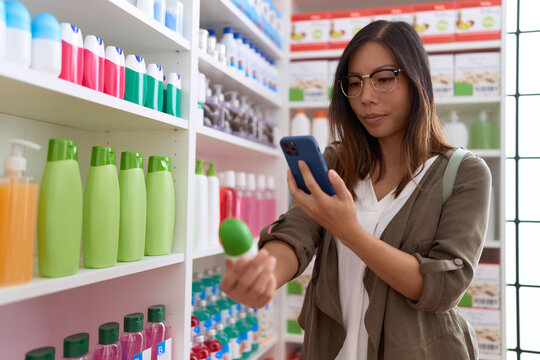 Young asian woman customer make photo by smartphone to medicine bottle at pharmacy