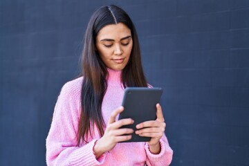 Young hispanic woman using touchpad at street