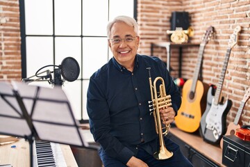 Senior man musician holding trumpet at music studio