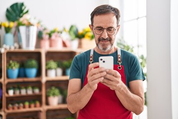 Middle age man florist smiling confident using smartphone at florist