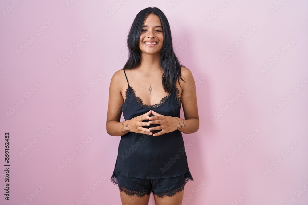 Poster brunette woman wearing black pajama hands together and fingers crossed smiling relaxed and cheerful.