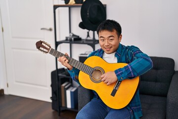 Obraz premium Young chinese man guitarist playing classical guitar at music studio