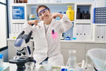 Hispanic girl with down syndrome working at scientist laboratory smiling cheerful showing and...