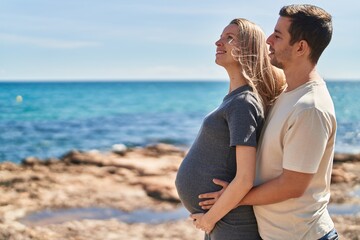 Man and woman couple hugging each other expecting baby at seaside