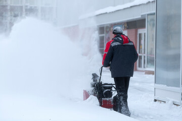 Fototapeta na wymiar A portable snow blower powered by gasoline. Snow removal in winter.