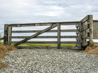 Wooden farm field gate with gavel road
